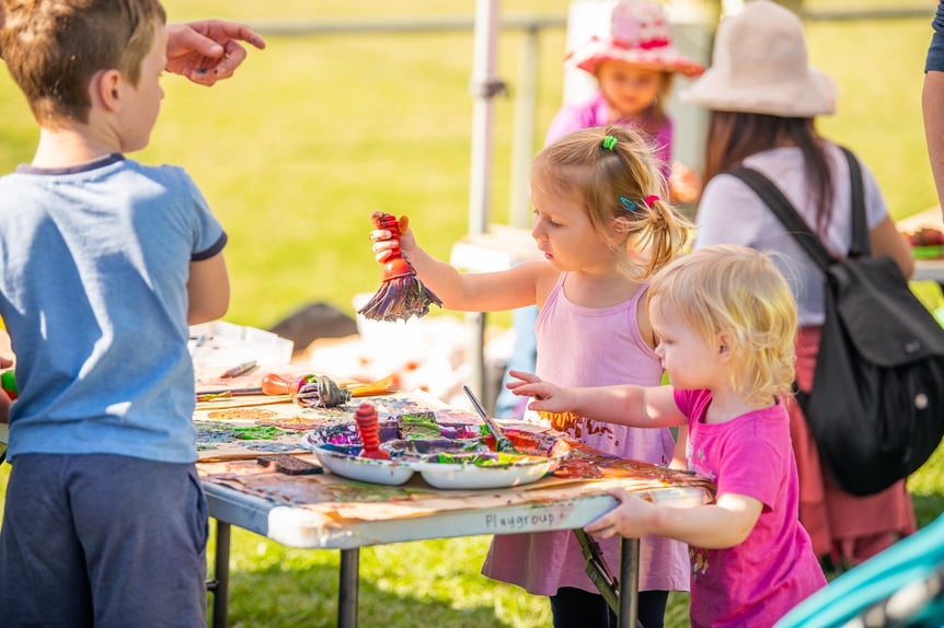 Children participating in messy creative play with paint and brushes at a Messy Play May event