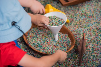 Sensory rice and funnel as part of a messy play activity