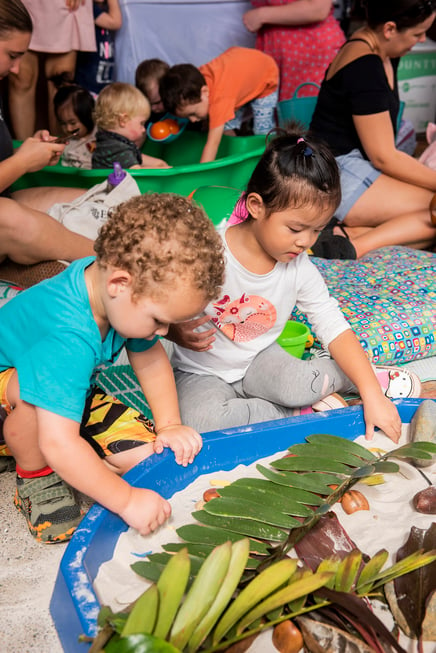 Children enjoying sensory play with sand and nature at a Messy Play May event