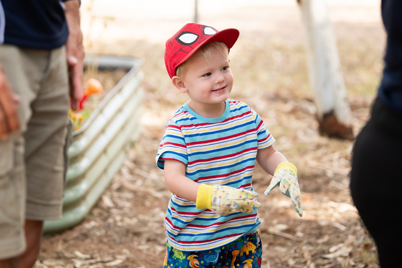 Child wearing gardening gloves and assisting on a gardening project at the Play Matters Australia Mt Isa Hub