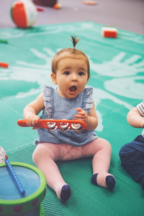 Baby mimicking facial expressions while playing a musical instrument