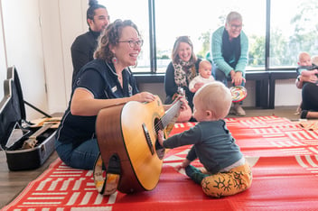 Child playing Play Matters Music Therapist's guitar